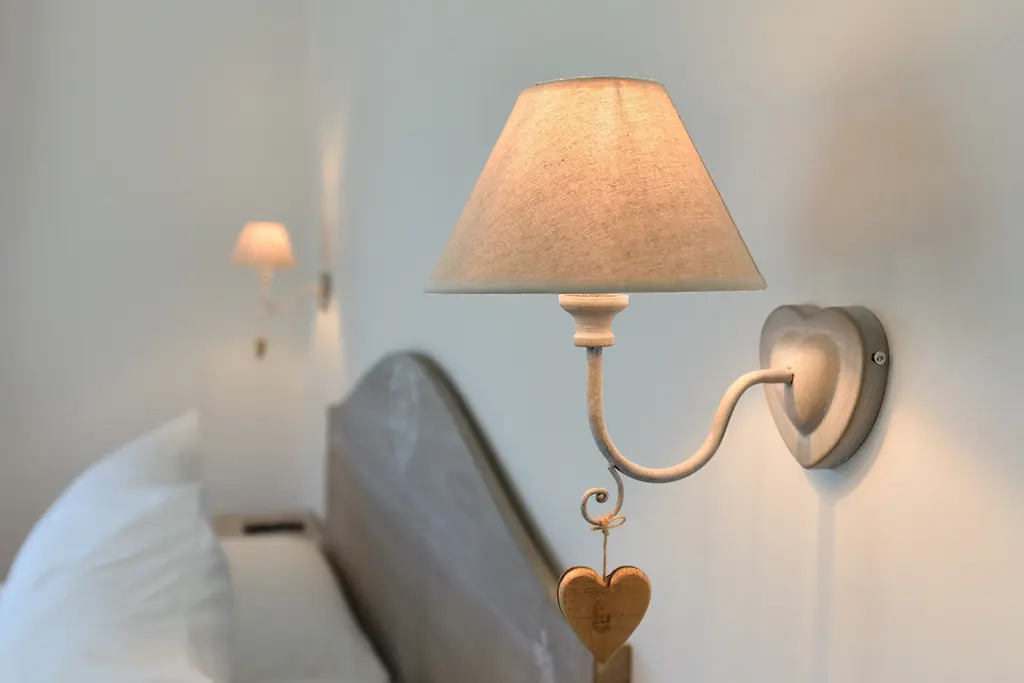 Lampada da parete in una stanza da letto con letto in legno e lampada simile sullo sfondo