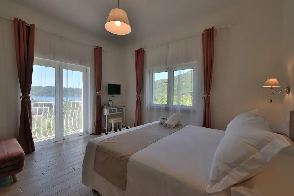 Camera da letto con letto matrimoniale, tende rosse e vista sul Lago di Nemi