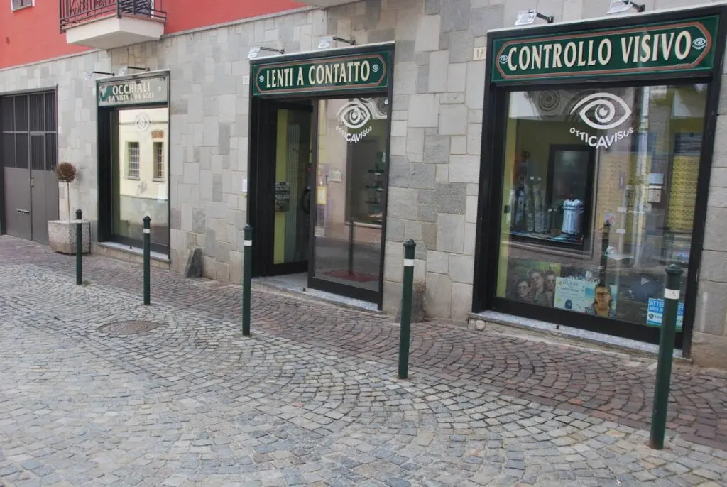 Ingresso di un negozio di ottica con tre vetrine, scritte "Occhiali", "Lenti a contatto" e "Controllo visivo"
